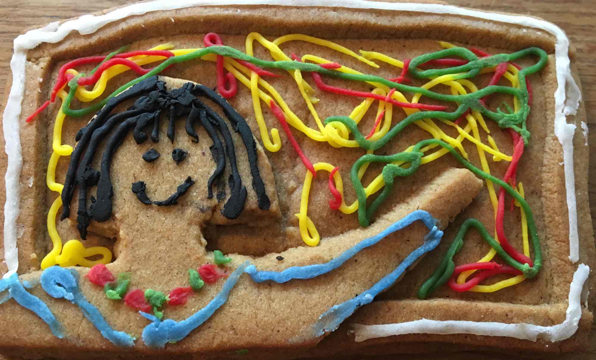 Gingerbread iced with smiling woman in front of painting