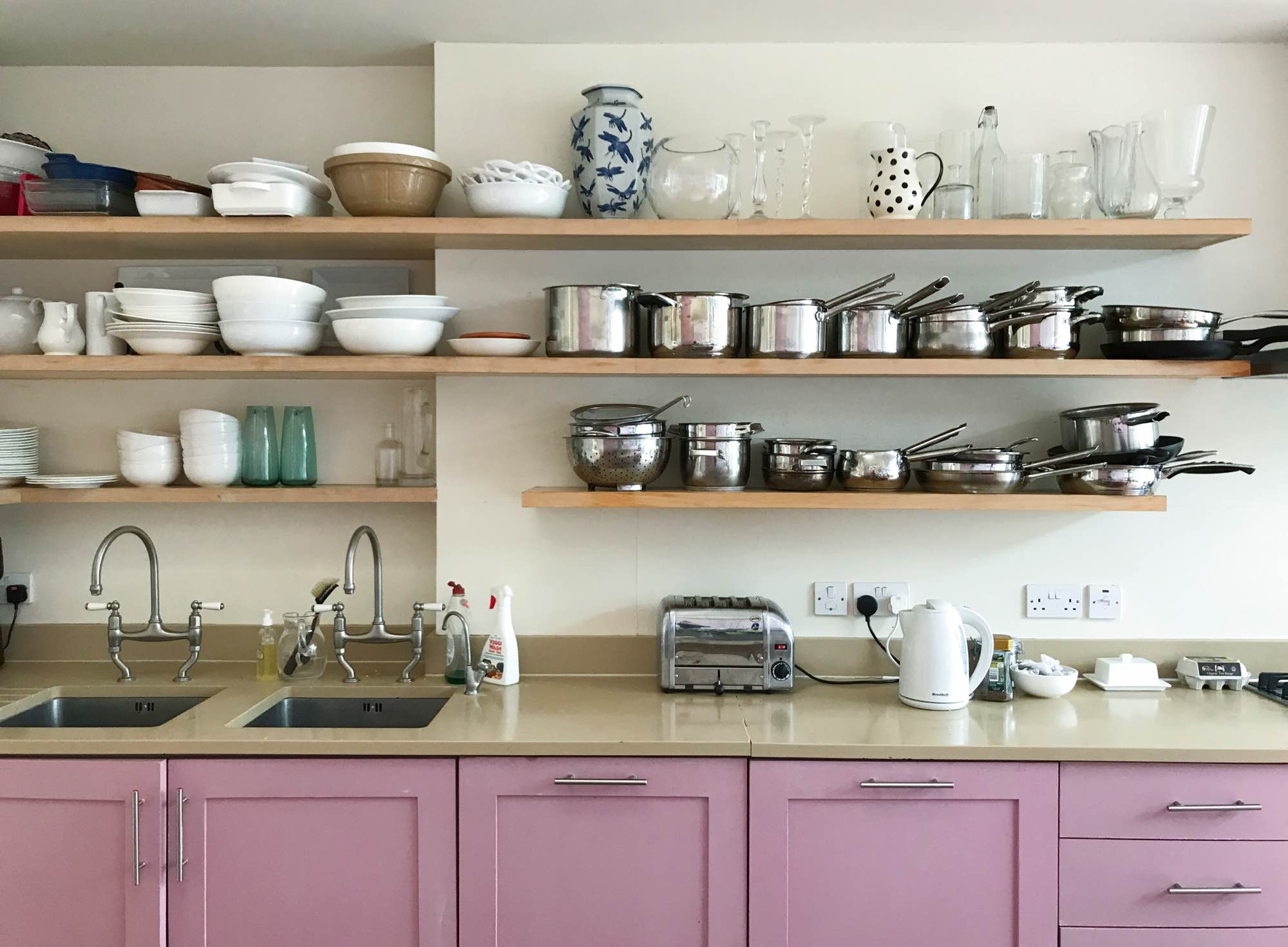 Open shelving in kitchen with pink cupboards