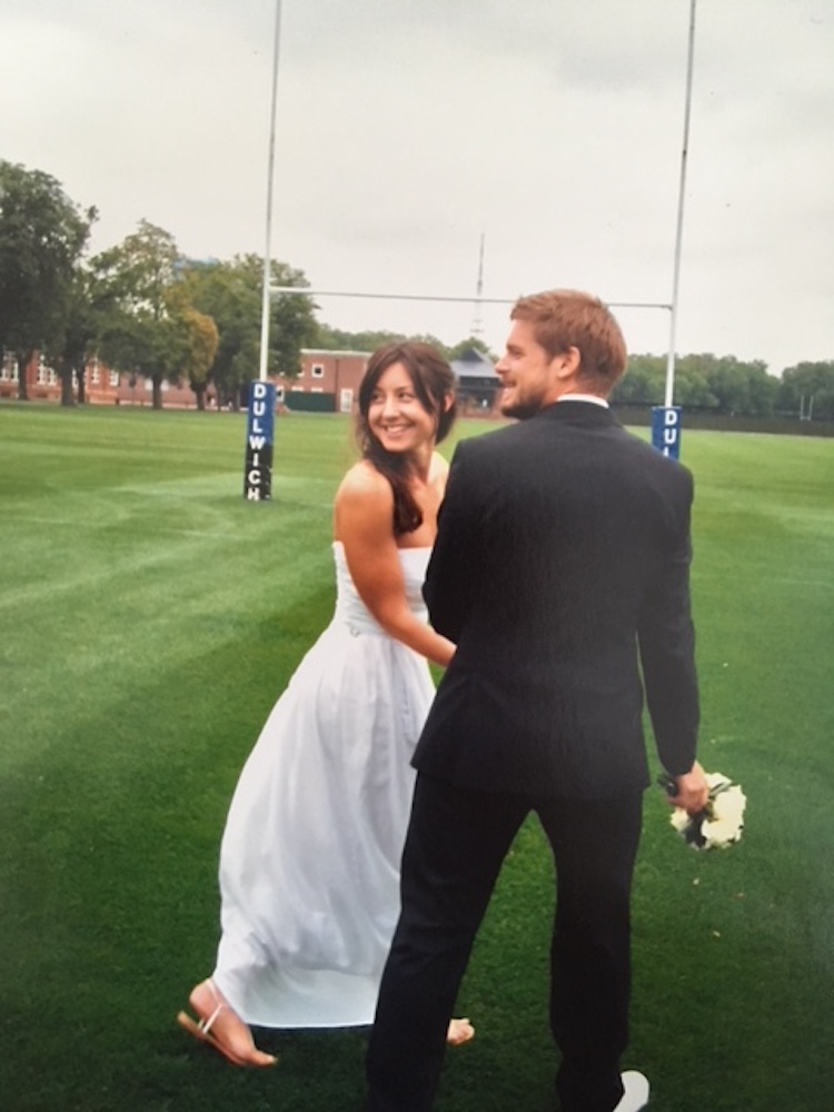 Bride and groom holding hands on a rugby pitch